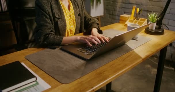 Una giovane donna con uno sguardo serio lavora a un computer portatile seduto a tavola in ufficio — Video Stock