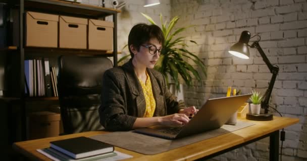 Una joven se quita las gafas, cansada de trabajar en el portátil — Vídeo de stock