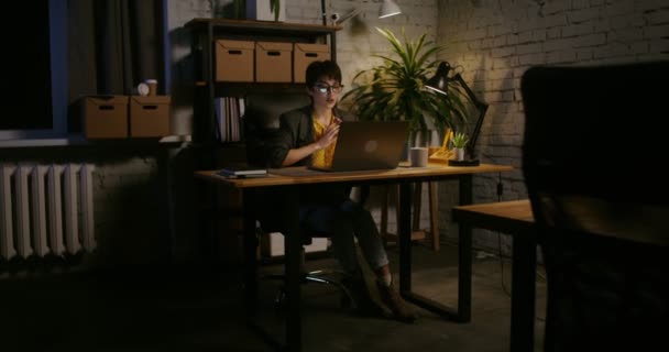 Žena mluví na video chatu na notebooku, sedí u stolu v kanceláři — Stock video