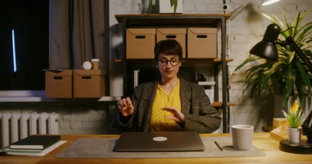 Une jeune femme s'assoit à la table, ouvre un ordinateur portable et commence à travailler — Video