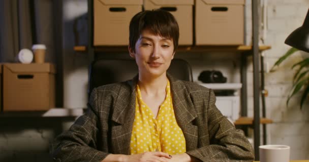 Una joven sonriendo mirando directamente a la cámara en una oficina moderna — Vídeo de stock