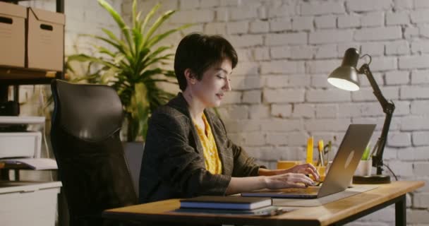 Bizneswoman pracująca do późna męczy się, zamyka laptopa i kładzie się na nim — Wideo stockowe