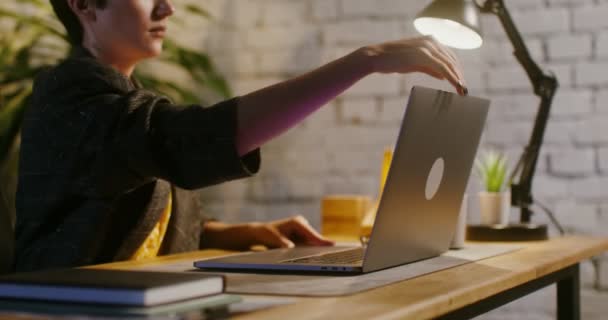 Mujer joven abre la tapa de la computadora portátil y comienza a escribir mientras trabaja en la oficina — Vídeos de Stock