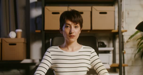 Junge Geschäftsfrau lächelt breit und blickt im Büro direkt in die Kamera — Stockvideo