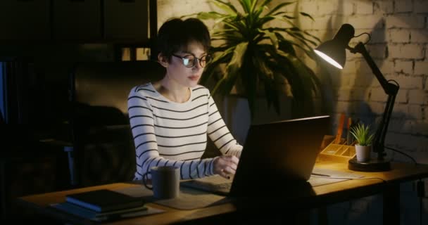 Egy fiatal üzletasszony kávét iszik, miközben egy laptopnál dolgozik az irodában. — Stock videók
