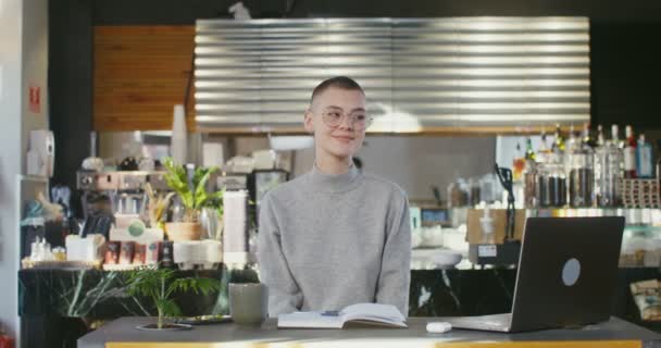 O femeie zâmbind uitându-se în camera de luat vederi a laptopului în cafenea — Videoclip de stoc