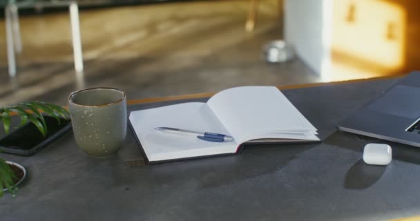 Un ordinateur portable ouvert et un bloc-notes se trouvent sur la table dans l'espace de coworking — Video