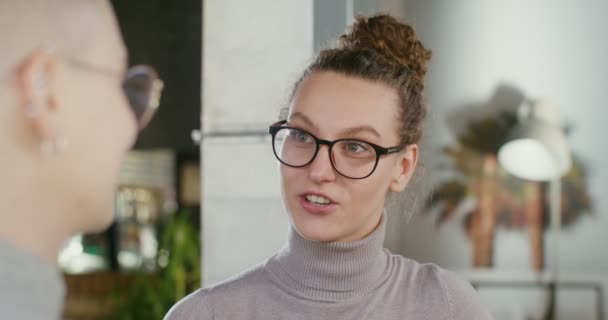 Een jong meisje drinkt koffie en praat met haar vriend in een koffiehuis in de stad. — Stockvideo