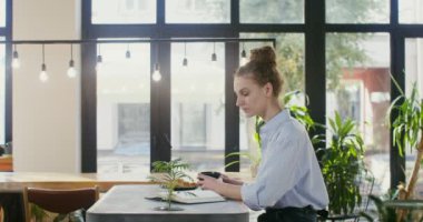 Güzel bir kadın kahve dükkanında otururken kitap okuyor ve çay içiyor.