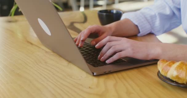 Les mains d'une femme à la peau claire tapant sur un ordinateur portable assis à une table dans un café — Video