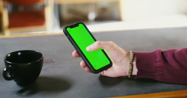 男人坐在桌边时，用的是绿色屏幕的电话 — 图库视频影像