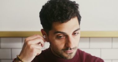 Genç adam kulaklık takıyor ve bilgisayarda görüntülü konuşmaya başlıyor.