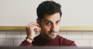 Genç adam kulaklık takıyor ve bilgisayarda görüntülü konuşmaya başlıyor.
