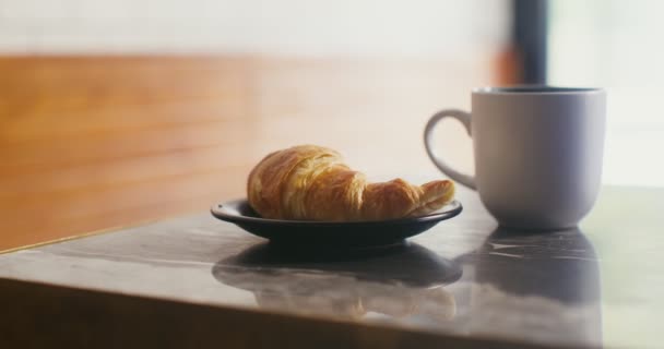 盘子里有一道开胃的羊角面包，小桌上有一大杯咖啡 — 图库视频影像