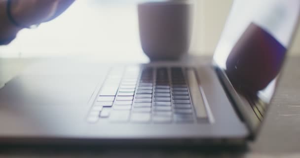 一个皮肤白皙的男人正坐在笔记本电脑上打字，坐在桌子旁边，特写 — 图库视频影像
