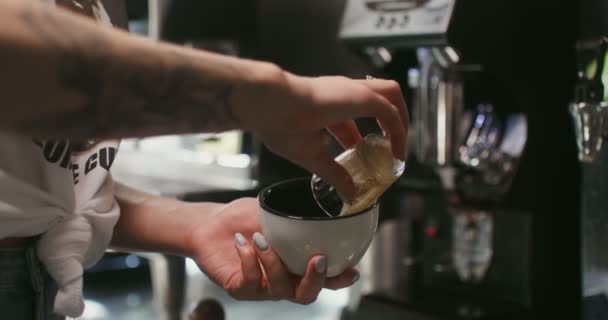Egy fiatal nő barista tetoválással a karján kávét főz egy kávézóban. — Stock videók