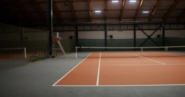 Turuncu kauçuk kaplı ve esnek ağlı boş bir tenis kortu.
