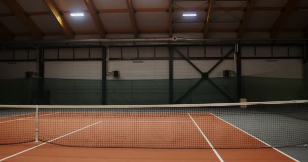 An empty indoor tennis court with orange rubber covering and stretched net — Stock Video