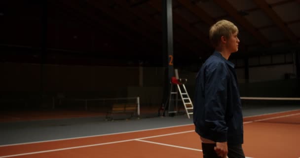 Un hombre entra en la cancha de tenis, llevando una canasta llena de pelotas de tenis — Vídeos de Stock