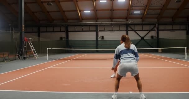 Um homem e uma mulher atirando bolas de tênis um para o outro, atingindo-os no chão — Vídeo de Stock