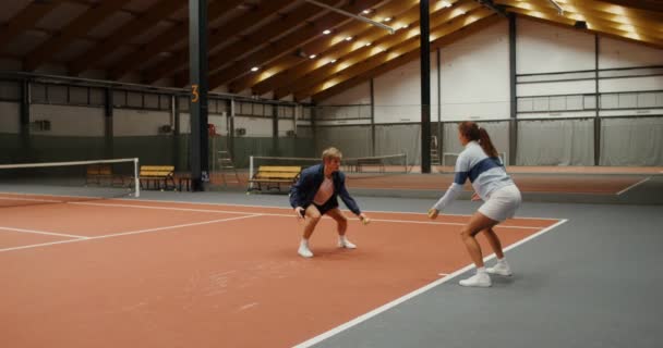 Un uomo e una donna che si lanciano palle da tennis, colpendole sul pavimento — Video Stock