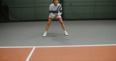 Genç bir kadın tenis topunun ilk atışını bekliyor.