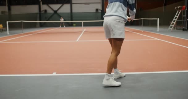 Молодые спортсмены играют в теннис в большом зале в одиночку, бросая мяч с ракеткой — стоковое видео