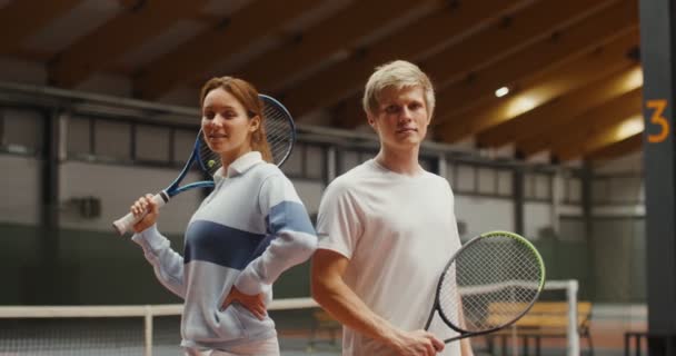 Jonge tennissers - een man en een vrouw glimlachen, kijken in de camera — Stockvideo