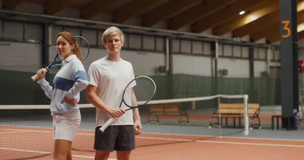 Junge Tennisspieler - ein Mann und eine Frau lächeln in die Kamera — Stockvideo