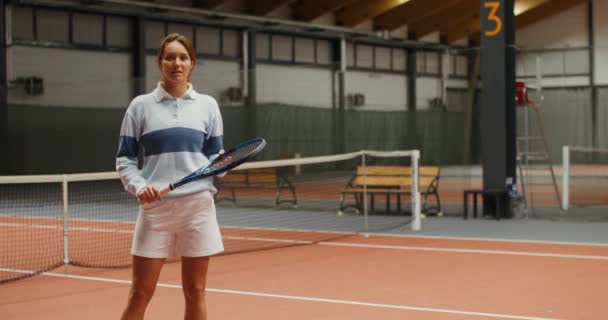 Giovane tennista sorridente che guarda nella fotocamera su un campo da tennis — Video Stock