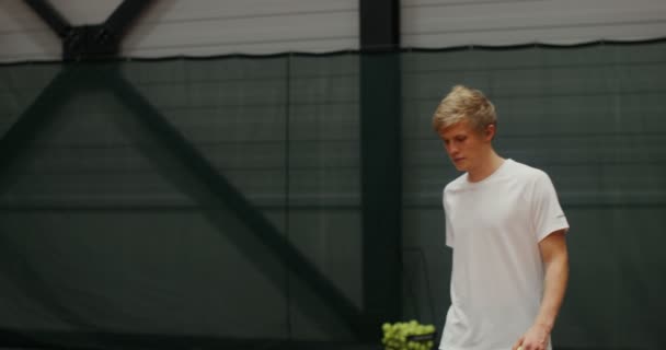 年轻的网球选手在室内网球场上用球拍打第一个球 — 图库视频影像