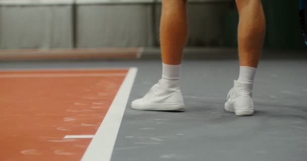 Närbild av benen på en ung manlig tennisspelare studsar samtidigt som bollen serveras — Stockvideo