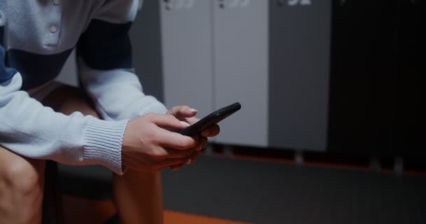 Mujer joven utiliza el teléfono mientras está sentado en el vestuario después de jugar al tenis — Vídeos de Stock