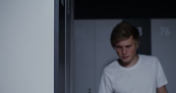 Jeune athlète masculin appuie sa tête contre le mur dans les vestiaires — Video