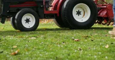 Beyzbol şapkalı genç adam traktör koltuğuna tırmanıyor ve işe hazırlanıyor.