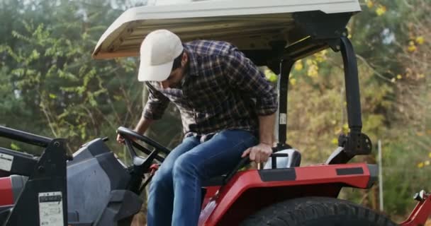 Mladík vyleze ze ze zemědělského traktoru a dokončí práci. — Stock video