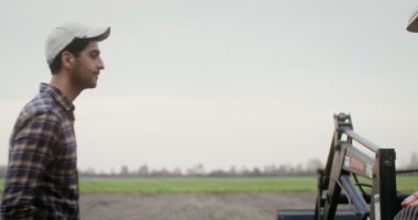 Bir adam traktörün direksiyonuna geçer, sabanı indirir ve tarlayı sürmeye başlar.