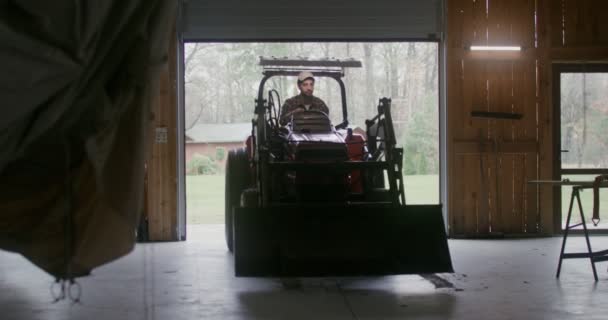 男は小さな農業用車両を運転して木のガレージに入った — ストック動画