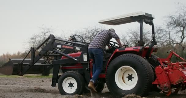 Jovem agricultor fica ao volante do veículo agrícola e começa a dirigir — Vídeo de Stock