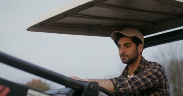 若い農家はトラクターに乗って周りを見回し、彼の財産を検査する — ストック動画