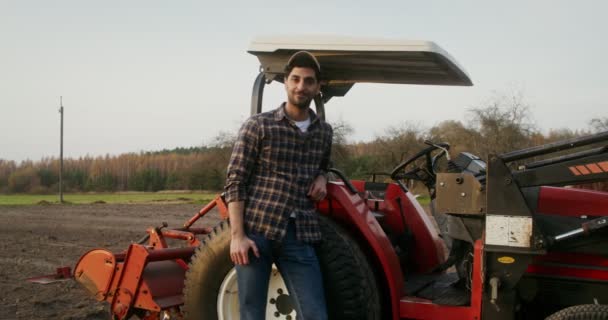 Ein Traktorfahrer lehnt an einer Maschine und lächelt in die Kamera — Stockvideo