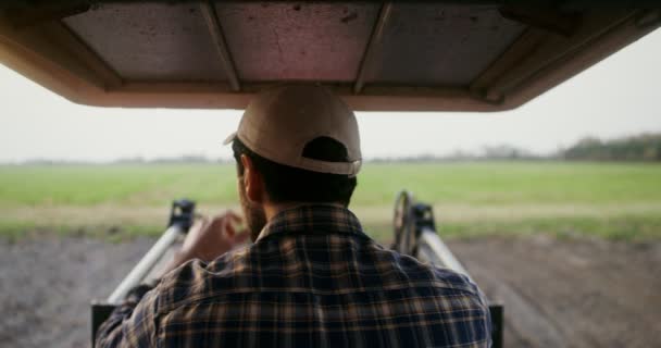 Close-up rear view of a tractor driver sitting at the wheel of an machine — Stock Video