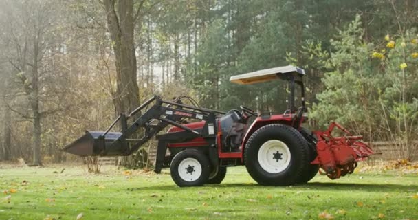 Современный сельскохозяйственный трактор стоит на ферме в осенний солнечный день — стоковое видео