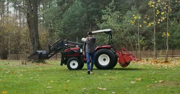 Young man climbs out of an agricultural vehicle tired after working in the field — Stock Video