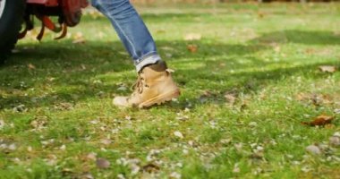 Beyzbol şapkalı genç adam traktör koltuğuna tırmanıyor ve işe hazırlanıyor.