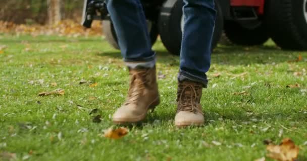 A man walking away from a tractor, male legs in stylish brown boots close-up — Stock Video