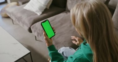 Yaşlı bir kadın elinde tuttuğu cep telefonunun ekranına bakıyor.