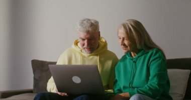 Yaşlı çift birlikte dizüstü bilgisayar kullanıyor, duygusal iletişim kuruyor ve tartışıyorlar.