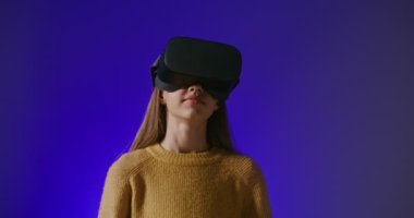 Sanal gerçeklik gözlüklü bir kız online bir oyun oynuyor, el hareketleri yapıyor.