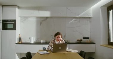 Kablosuz kulaklıklı genç adam laptoptaki bir video görüşmesinde konuşuyor.